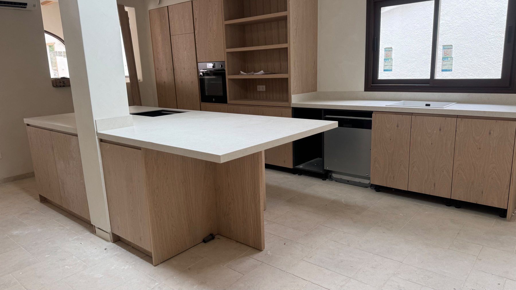 Kitchen in oak with stone worktops, oven and open shelving installed.