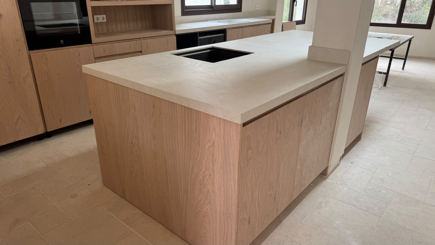Sea House kitchen: oak cabinetry and a pale stone island, freshly installed.